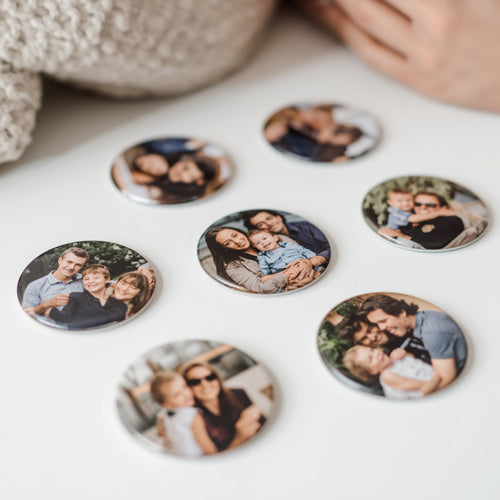 Round photo magnets with family images on a white surface